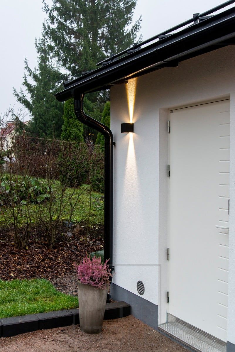 En svart FUNK-vägglampa med dubbelriktad belysning för att framhäva och belysa dörren. Ledstore.fi