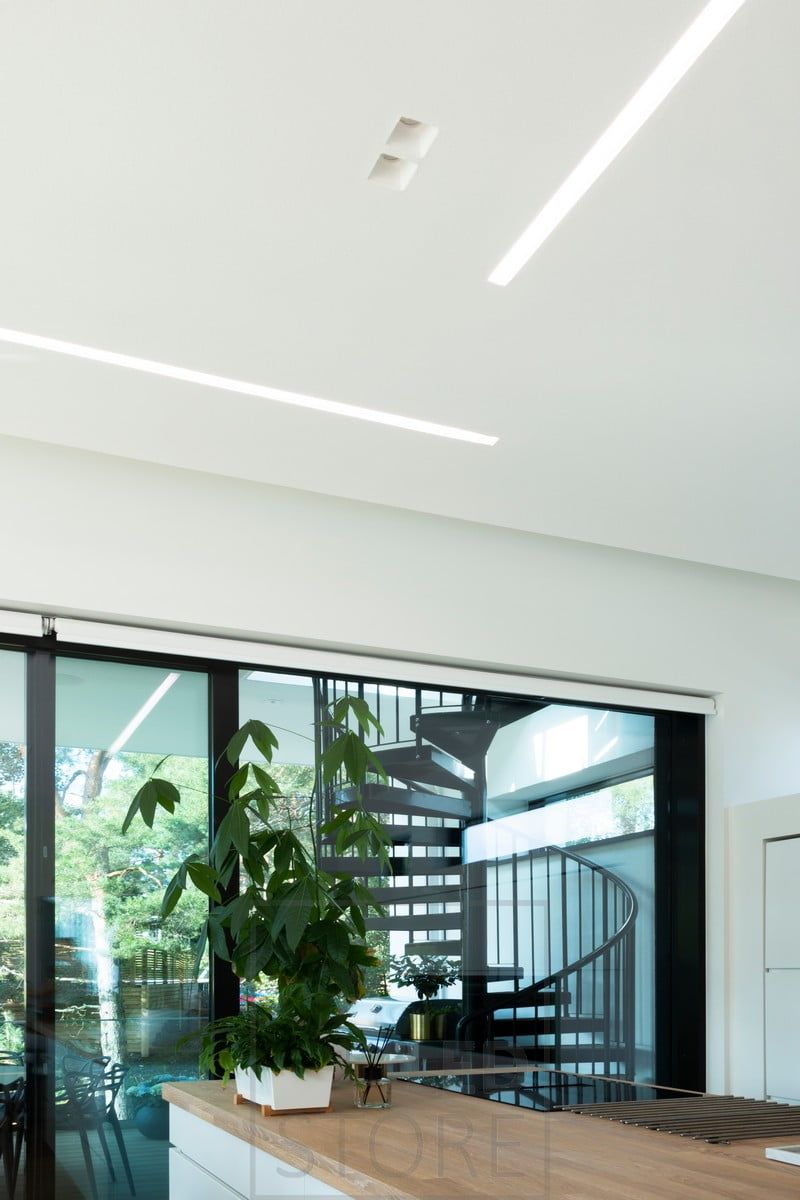 En bred uppo-profil kombinerad med spotlights för att skapa allmänbelysning i ett stort vardagsrum med öppen planlösning. Ledstore.fi