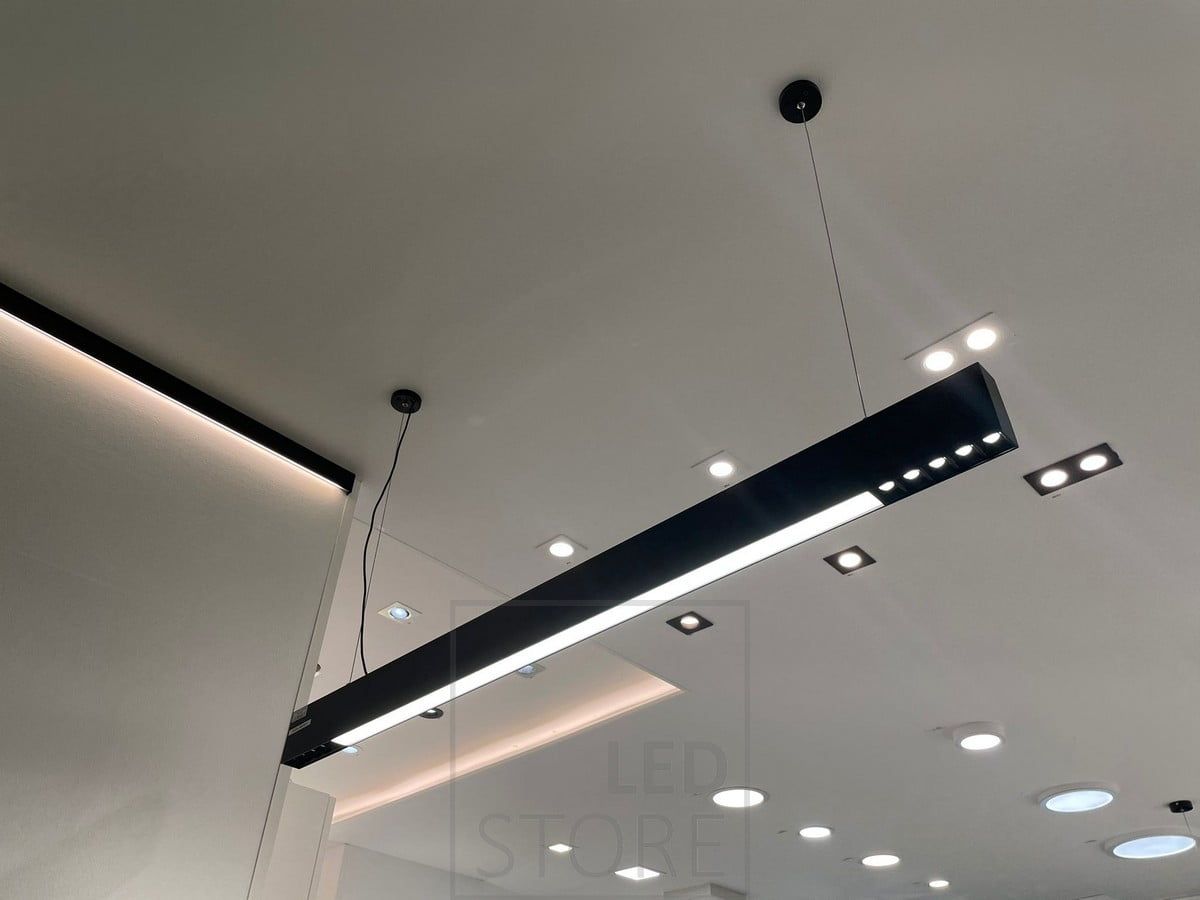 Armatur Ledstorella Viiva ovanför försäljningsdisken. Ledlist på utbytbar aluminiumprofil i taket för indirekt ljus samt spotlights och panelbelysning i taket. Ledstore.fi