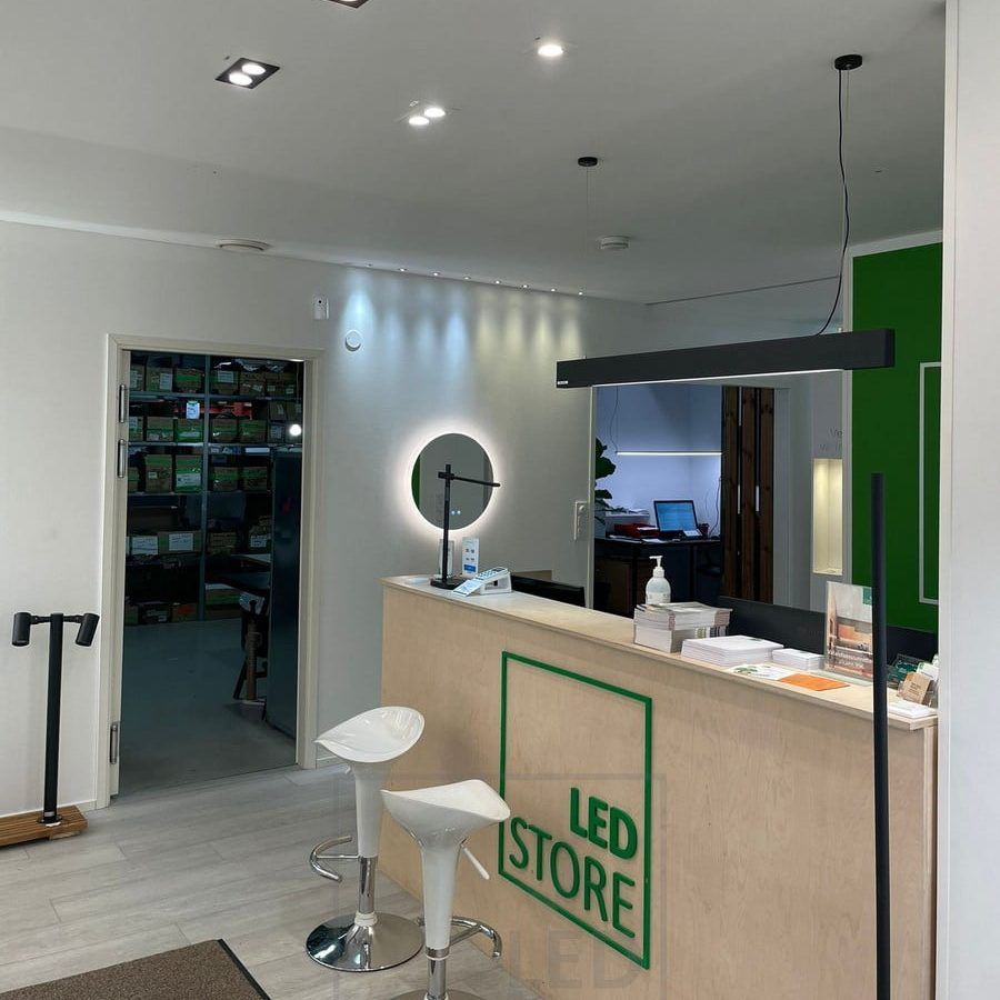 Led-lampor i Ledstores showroom. Spots i taket framför disken och en VIIVA taklampa ovanför disken. Väggen accentueras av 3W spotlights, fasta och riktbara. Moon 600 ljusspegel under spotarna. Ledstore.fi