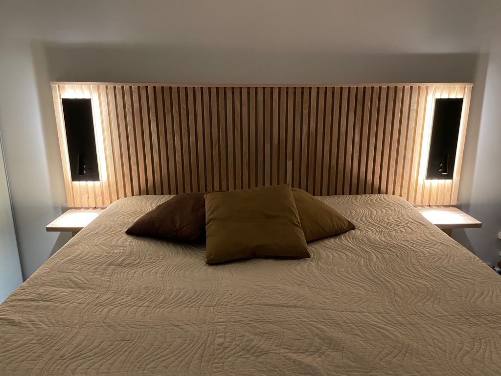 Svarta NIGHT vägglampor vid sängens huvudända. Armaturen har ett riktat läsljus och ett indirekt stämningsljus. Ledstore.fi