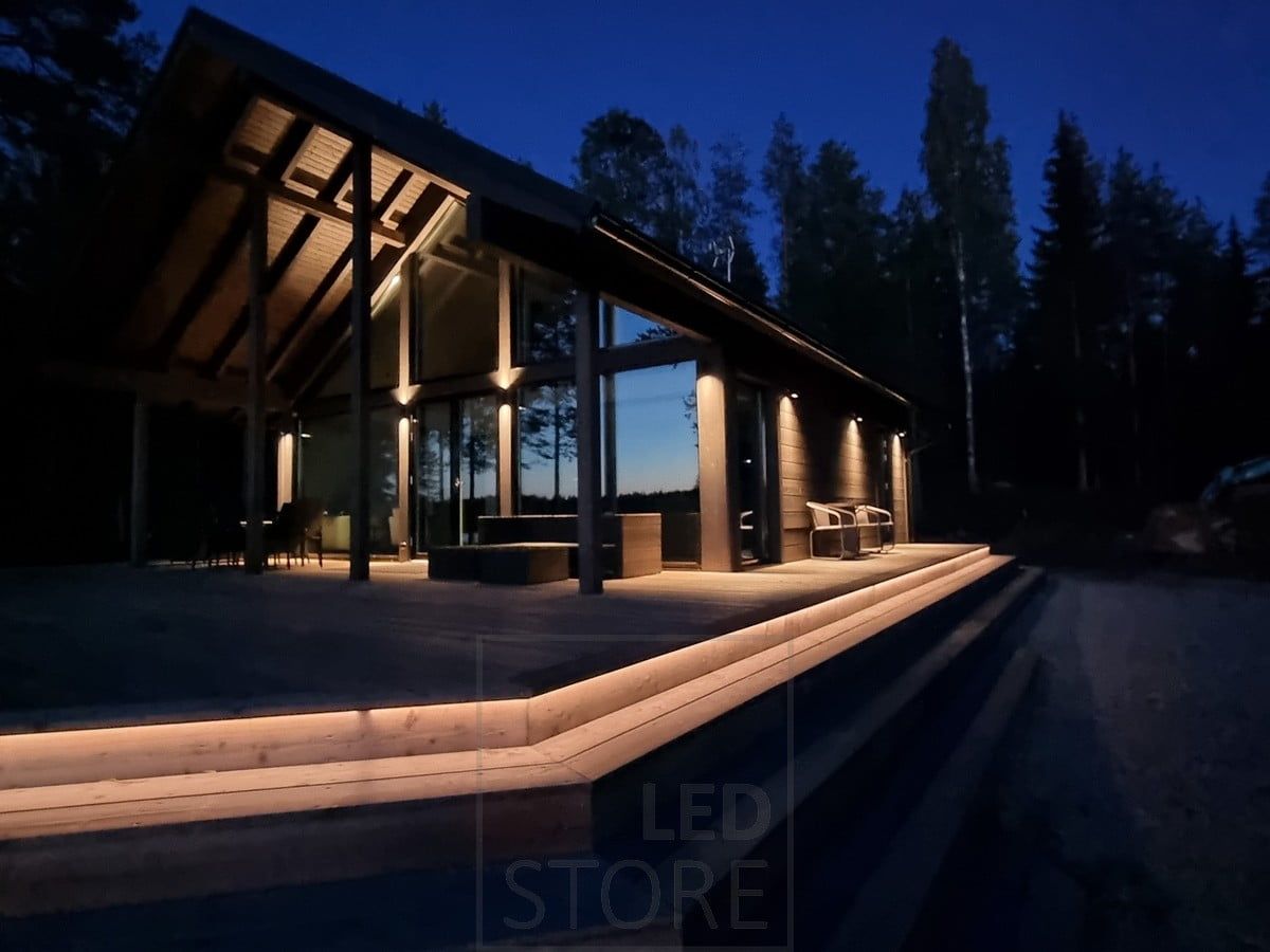 Mångsidig och stämningsfull utomhusbelysning med LED-list i trappan och vägglampor. Vägglampor som lyser i två riktningar vid en hög punkt och i en riktning vid en lägre punkt. Ledstore.fi