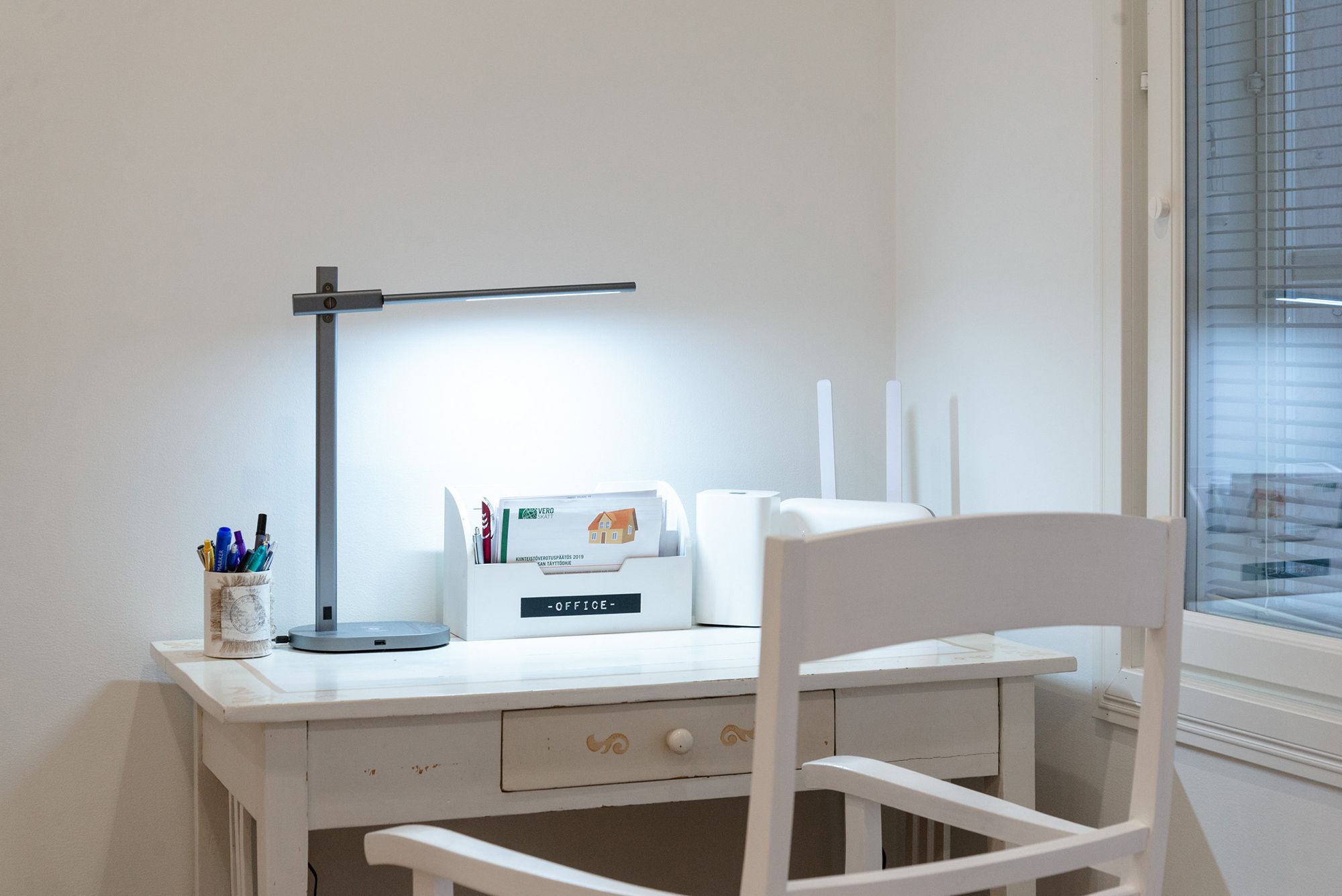 En kranbordslampa som lyser upp en arbetsstation. Led-bordslampa KURKI nattduksbordslampa och läslampa i ett. KURKI är en grå, enkel och elegant lampa med metallram. KURKI led-bordslampa ger ljus direkt eller indirekt tack vare den fritt justerbara stommen. Trådlös laddning och USB-laddning för din telefon. Färgtemperatur justerbar och dimbar. Ledstore.fi