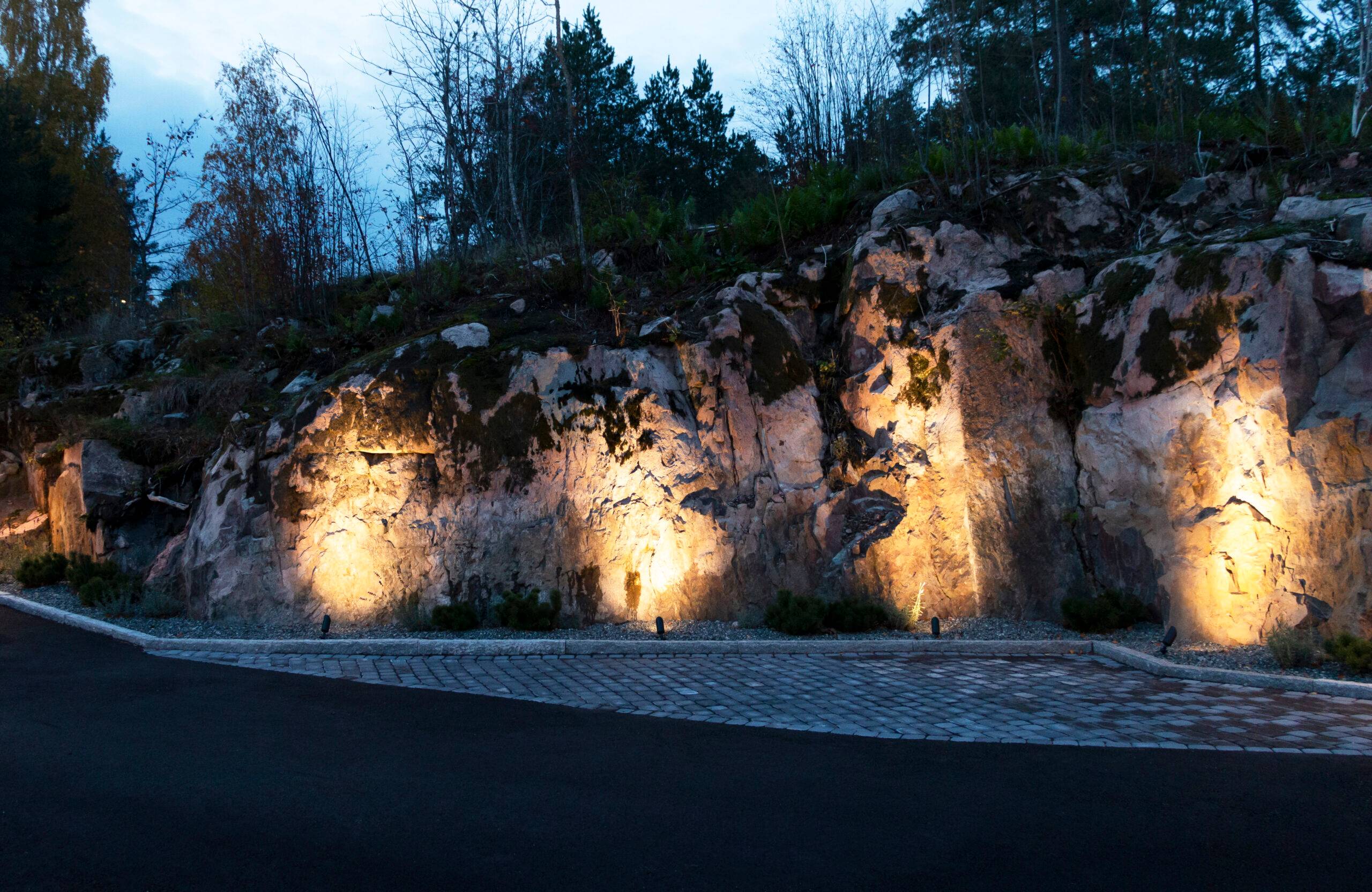 Vid kanten av den steniga innergården accentuerar LED-landskapsbelysning de grova formerna.
