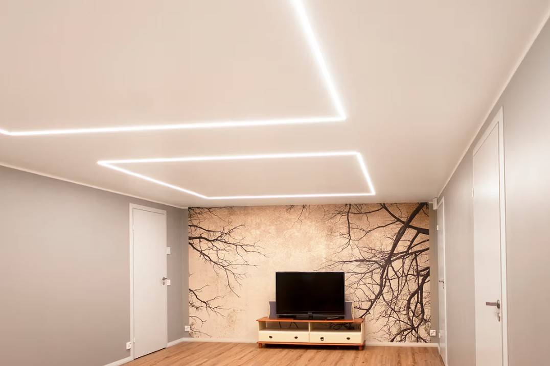 Ett minimalistiskt vardagsrum i ett familjehem i Kaitamäki, Esbo, där LED-taklampor från LedStore.fi skapar ett elegant belysningsschema. Vardagsrummet har ett TV-bord och en slående väggmålning som framhävs av LED-belysning av hög kvalitet.