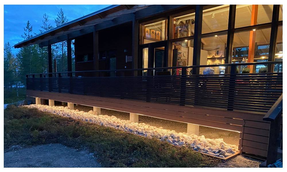Upplyst LED-band på terrassens sockel i skymningen.