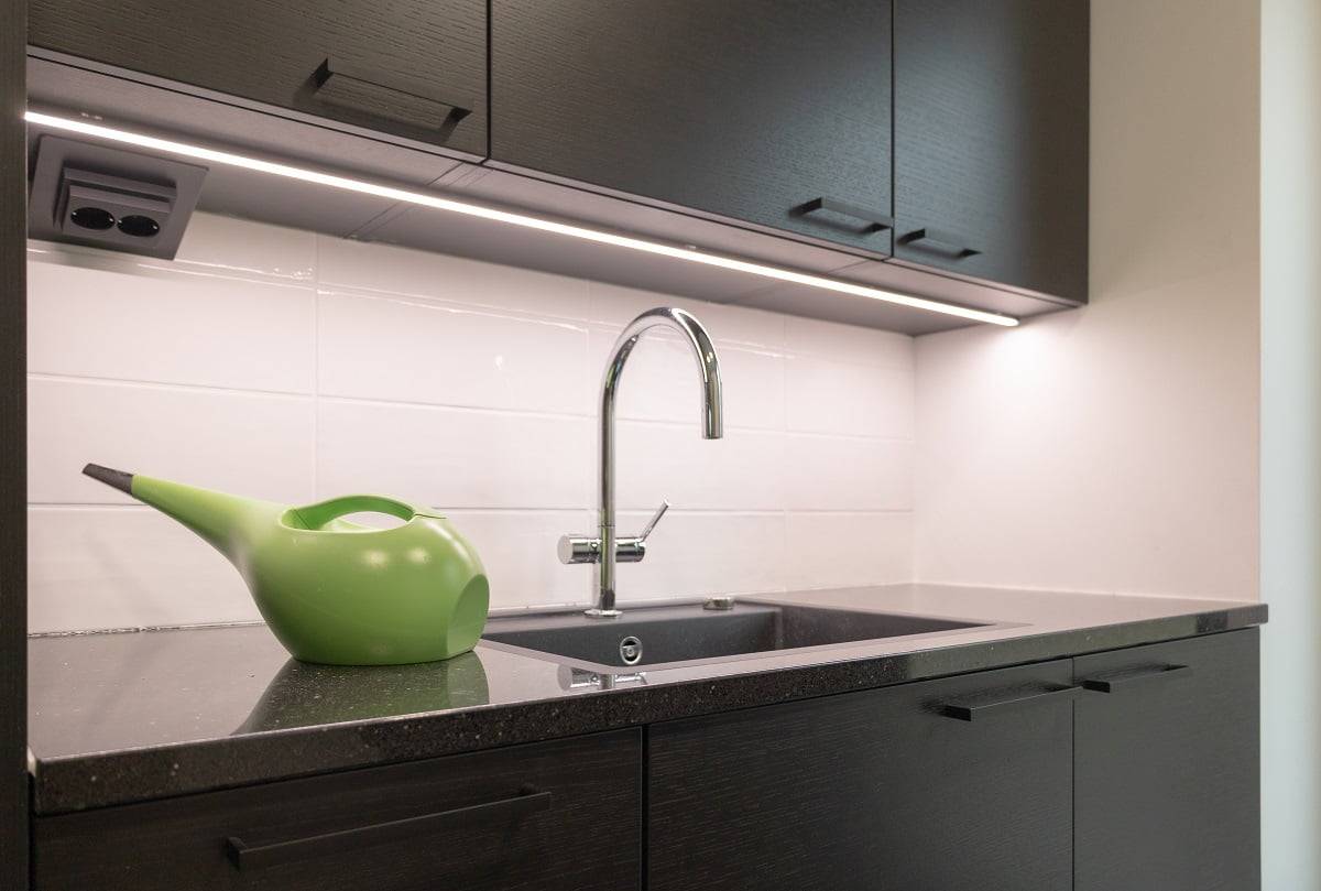 På bänkskivan i tvättstugan lyses den mörka ytan upp av en LED-remsa i en svart aluminiumprofil. ©LedStore