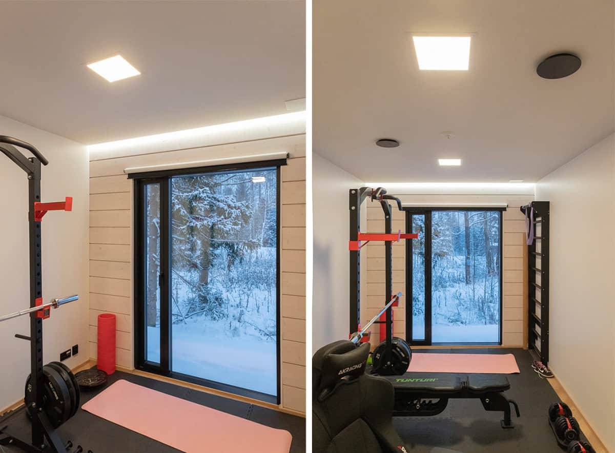 Ett litet gym med ett stort fönster utåt, två små panellampor i taket och en led-remsa ovanför fönstret.