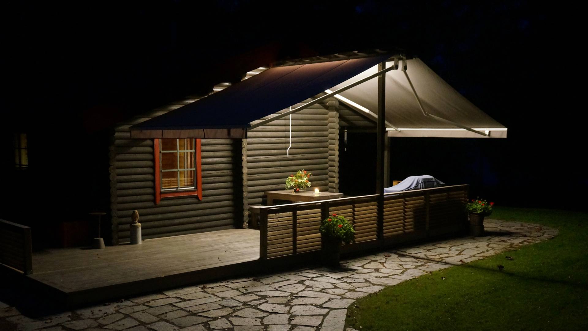 LED-lampor som är fästa på baldakinens undersida belyser terrassytan och den stenlagda gångvägen nedåt. Ljuset reflekteras inte uppåt. 