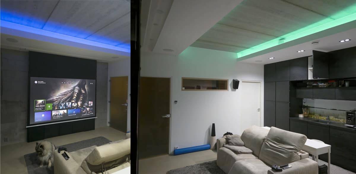Modernt vardagsrum med LedStore.fi LED-belysning för hemmabio, projektorduk, bekväma sittmöbler och en hund på golvet.